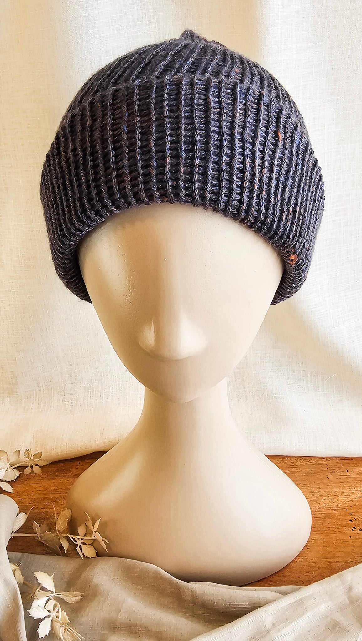 Knitted gray beanie on a mannequin head against a neutral background
