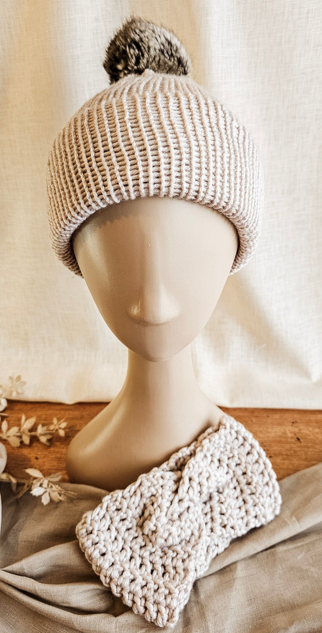 Knitted beige headband on a mannequin head with a neutral background