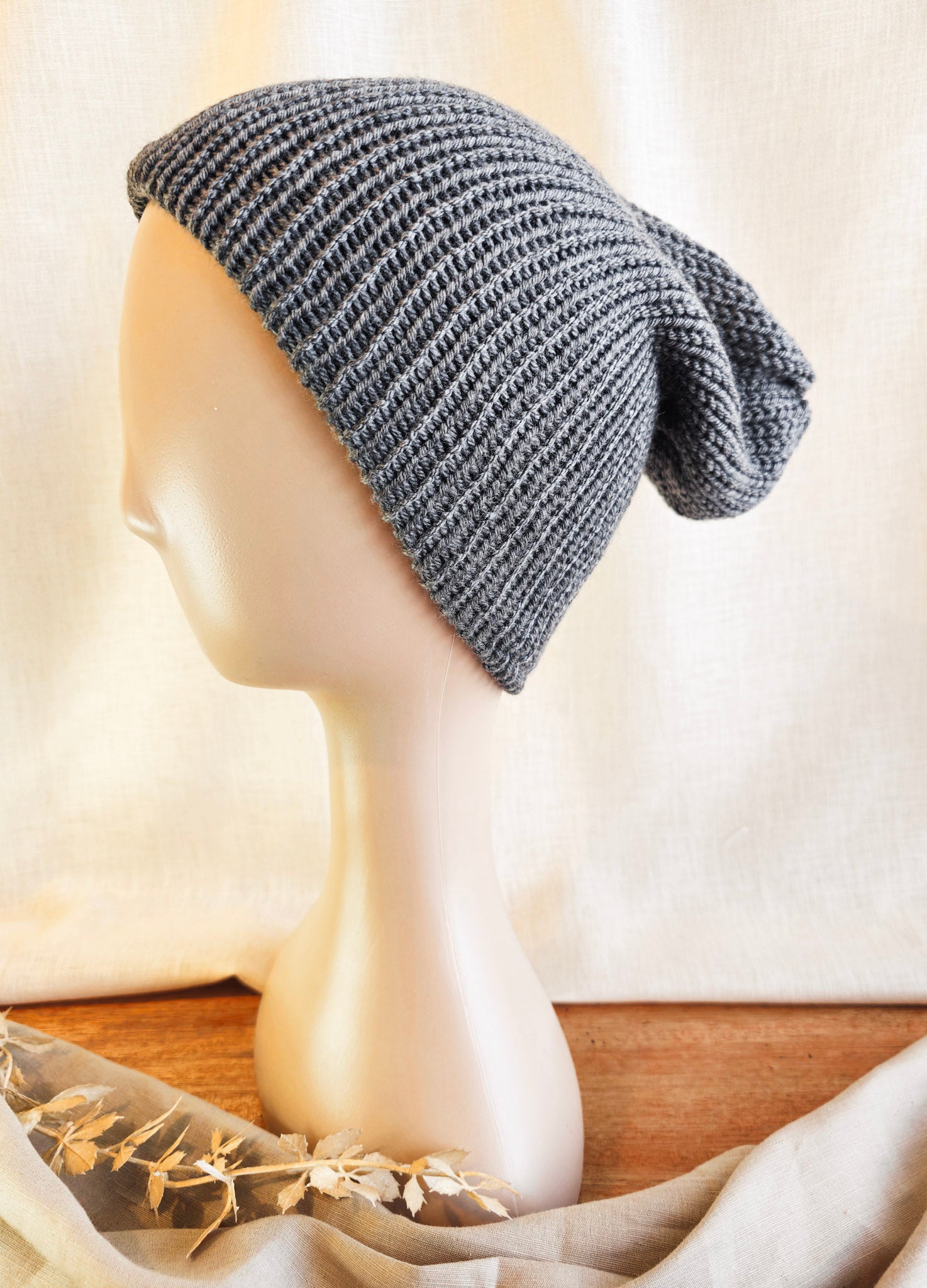 Gray knitted beanie on a mannequin head against a neutral background