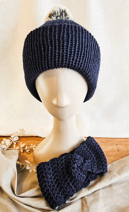 Navy blue knitted beanie and headband set on a mannequin head with a neutral background