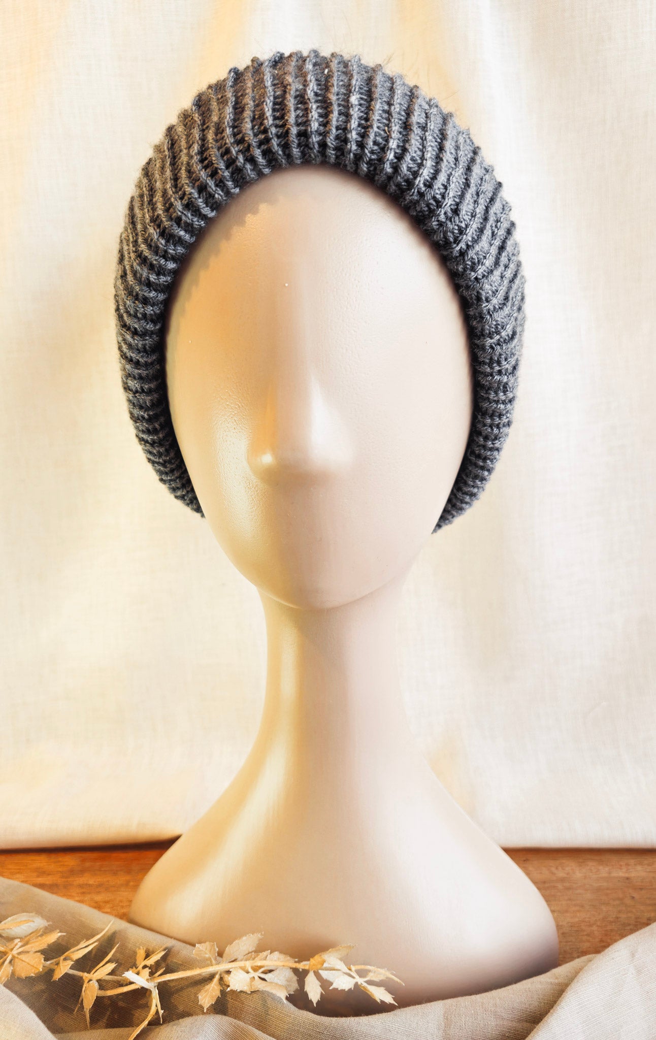 Gray knitted headband on a mannequin head with a neutral background