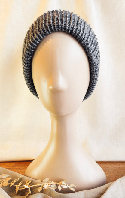 Gray knitted headband on a mannequin head with a neutral background