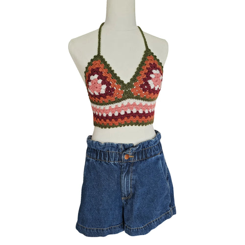Colorful crochet top and denim shorts on a mannequin against a white background