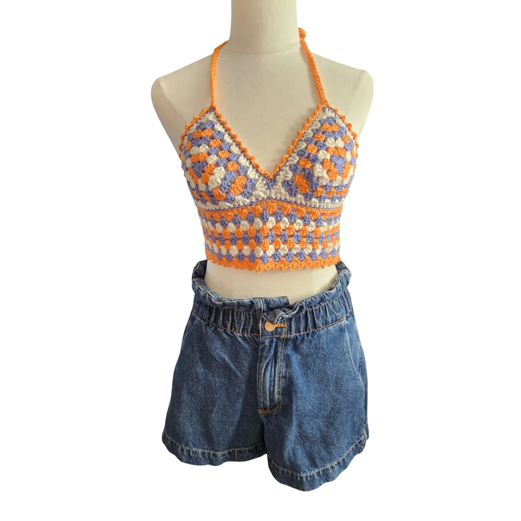 Colorful crochet top and denim shorts on a mannequin against a white background