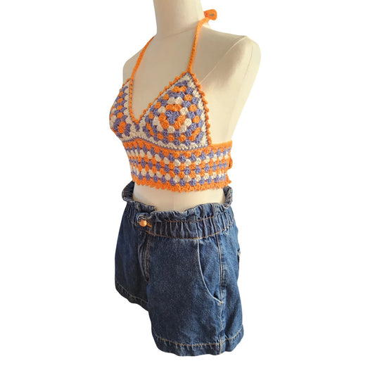 Mannequin wearing a colorful crochet top and blue denim shorts on a white background