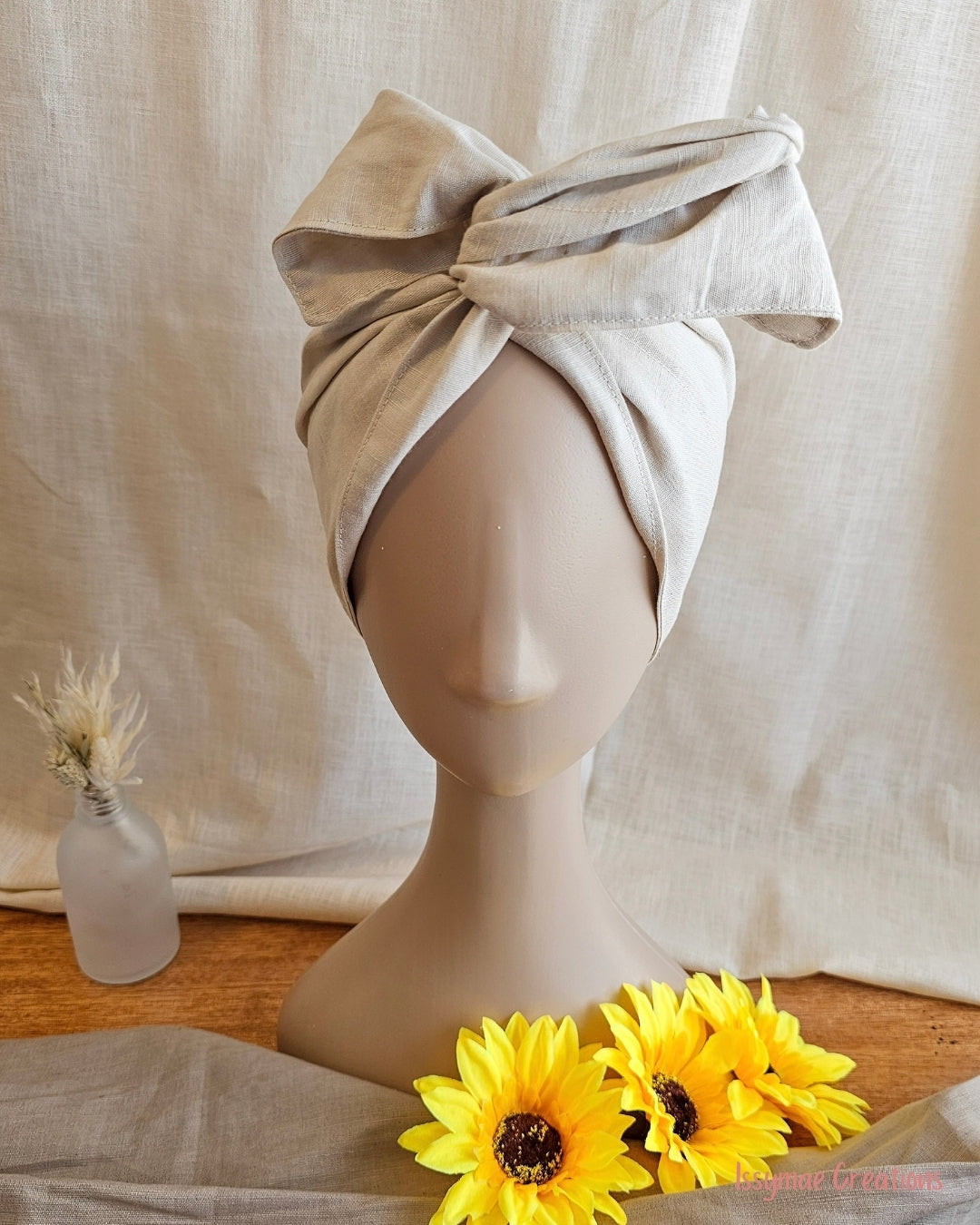 mannequin wearing a ladies wire head wrap with sundlfowers and linen back ground