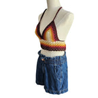 Colorful crochet top and blue denim shorts on a mannequin against a white background