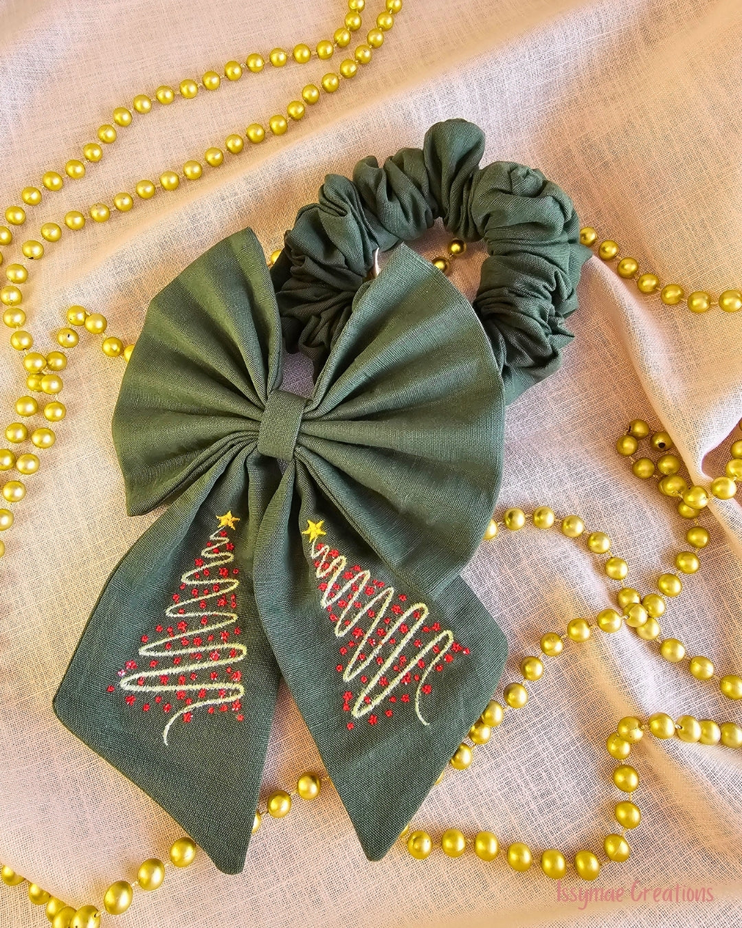 Green embroidered bow and hair scrunchie Christmas theme on cream background with gold beads