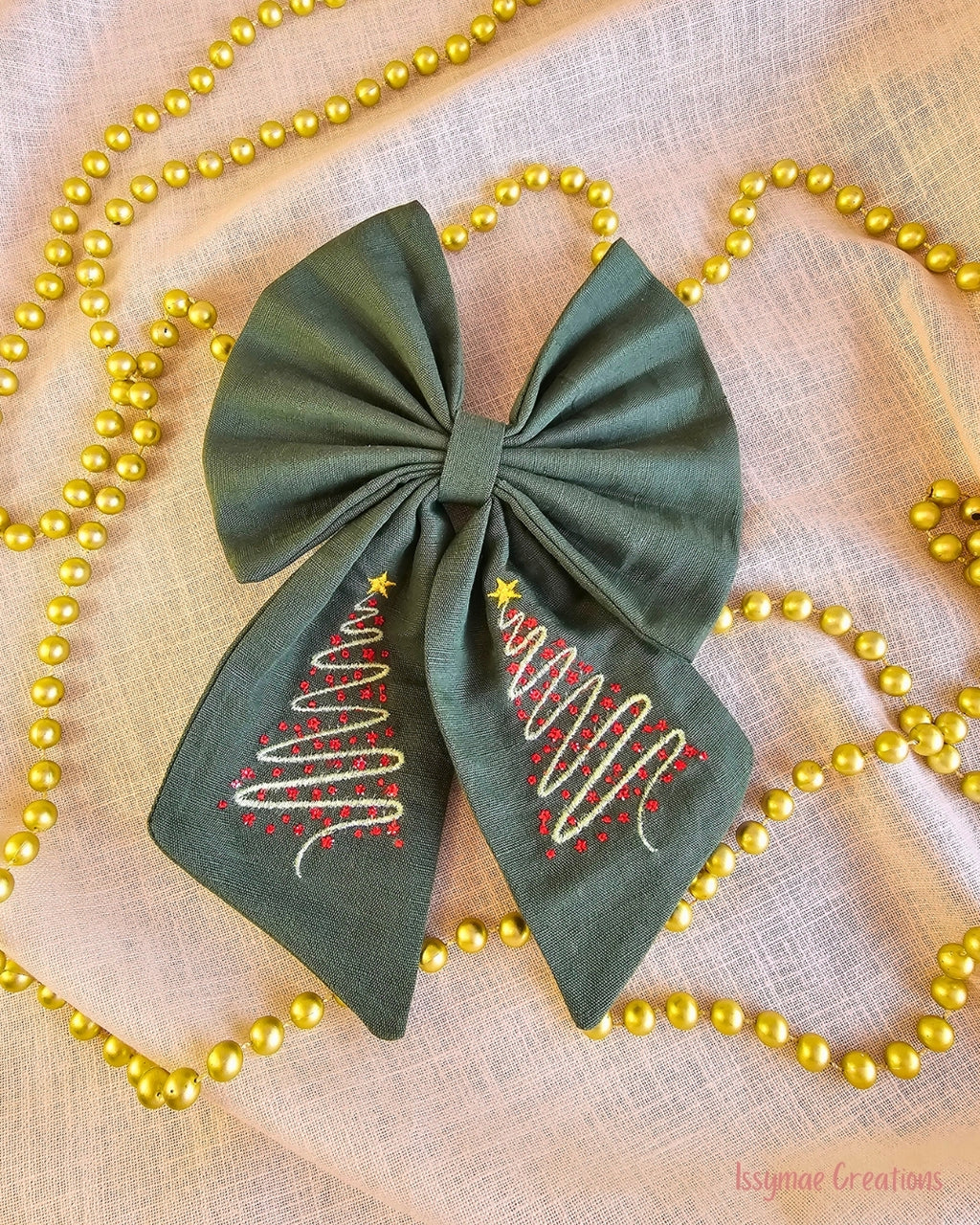 Green Hair Bow with embroidery on a cream back ground with gold beaded chain