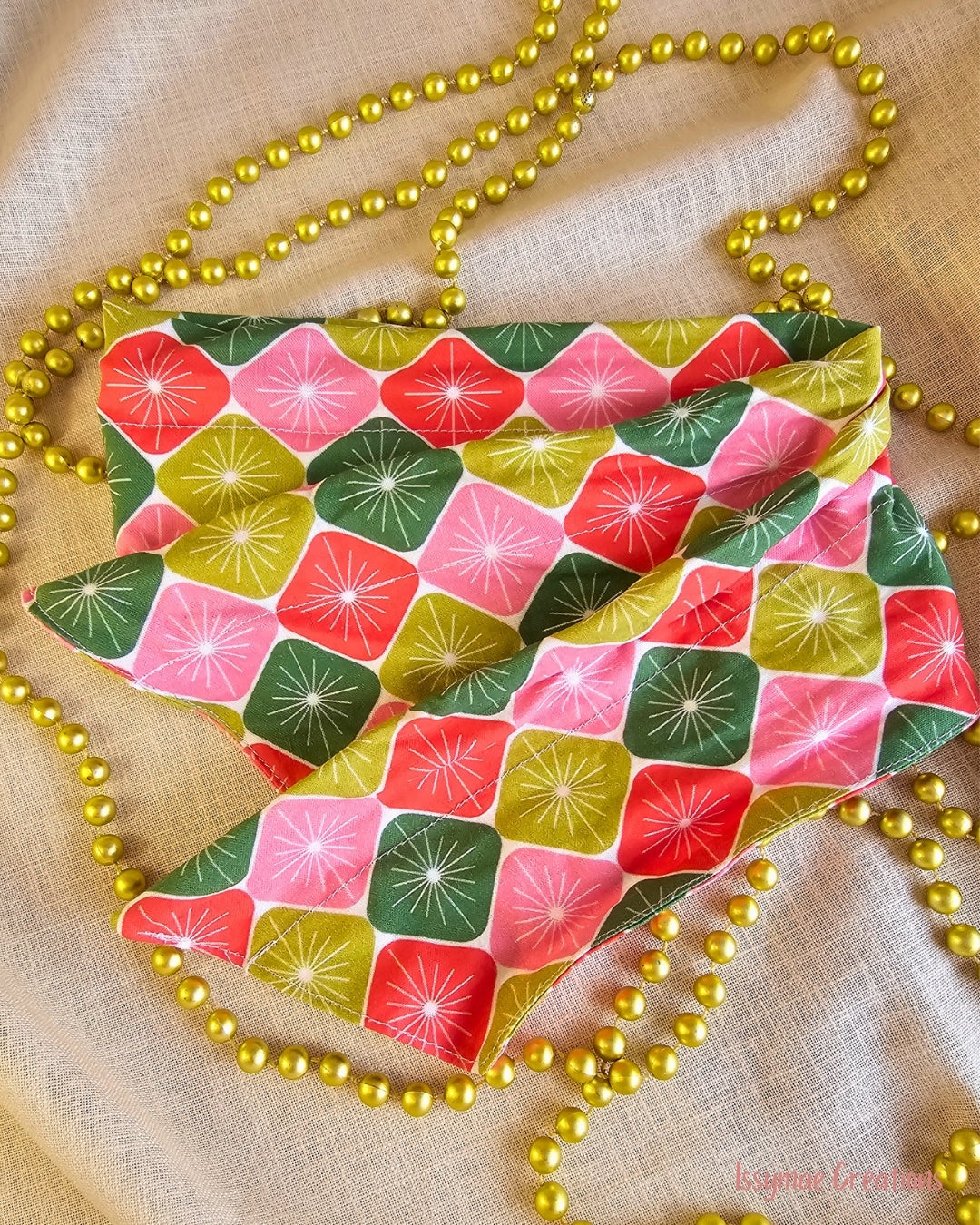 Merry Starburst wire head wrap laid flat, showing pink, red and green retro starbursts, surrounded by gold beads.