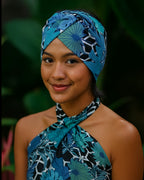 Woman wearing a blue patterned headband and dress against a dark background