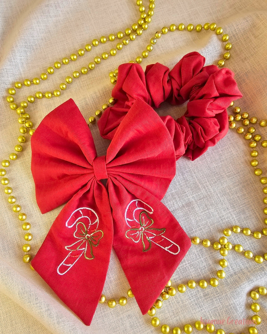 Red bow and scrunchie on a cream back ground with gold beades