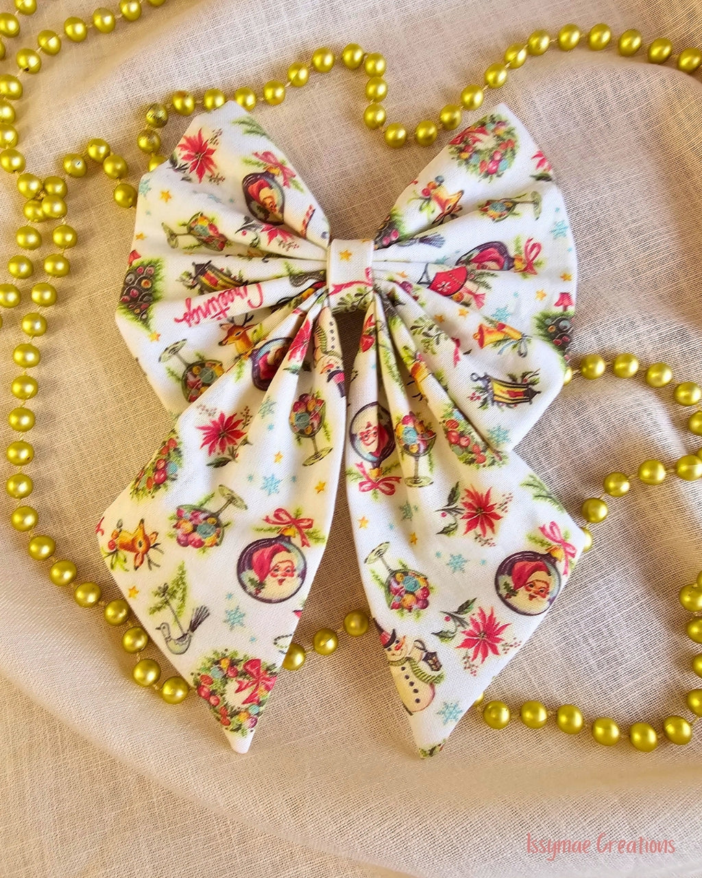 Christmas pattern hair bow that is on a cream background with gold beads
