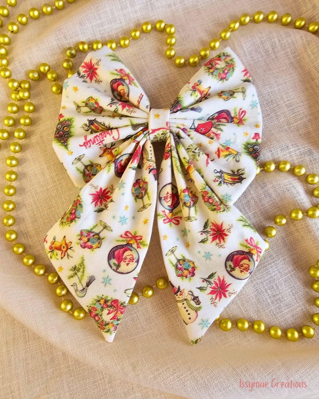 Christmas pattern hair bow that is on a cream background with gold beads
