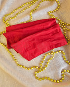 Santa Baby red wire head wrap laid flat on cream fabric with gold Christmas beads.