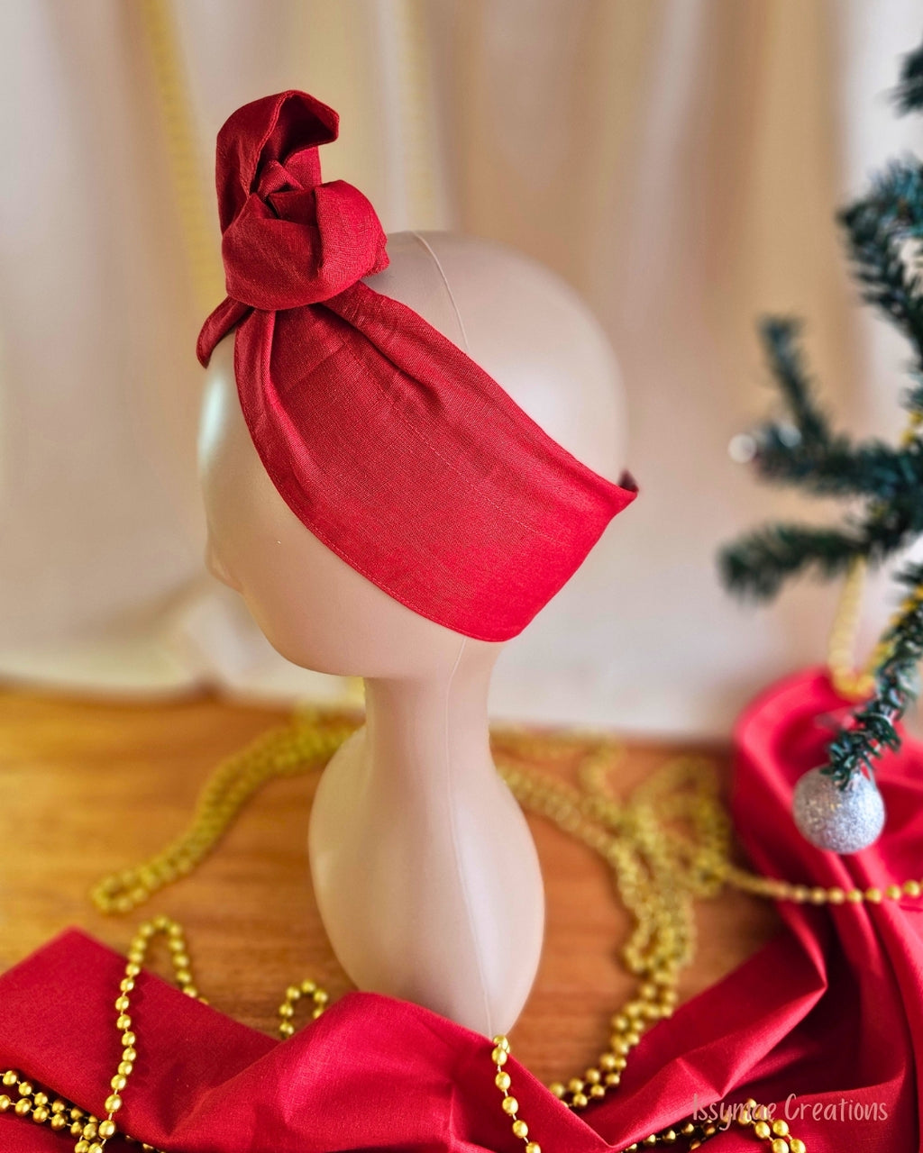 Side view of the Santa Baby red wire head wrap showing the wide fabric band and twisted knot.