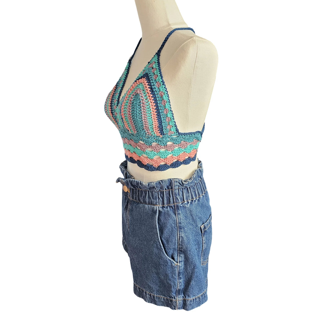 Mannequin wearing a colorful crochet top and blue denim shorts on a white background