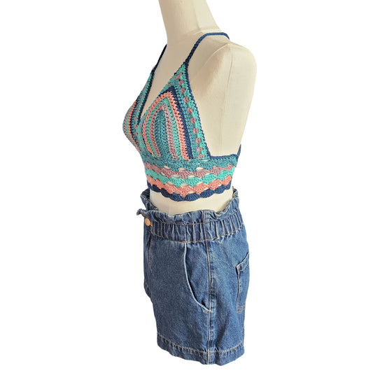 Mannequin wearing a colorful crochet top and blue denim shorts on a white background