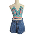 Mannequin wearing a colorful crochet top and blue denim shorts on a white background
