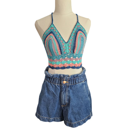 Mannequin wearing a colorful crochet top and blue denim shorts on a white background