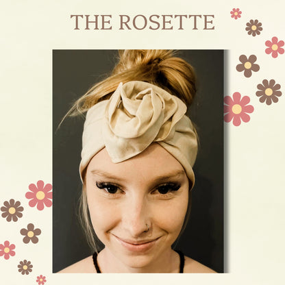 A woman wearing a beige fabric wire headband with a large rosette flower detail, styled in a messy bun. The image is framed with a cream border featuring the text 'THE ROSETTE' and retro-style floral illustrations.