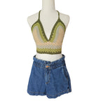 Mannequin wearing a green and beige crochet top with blue denim shorts on a white background