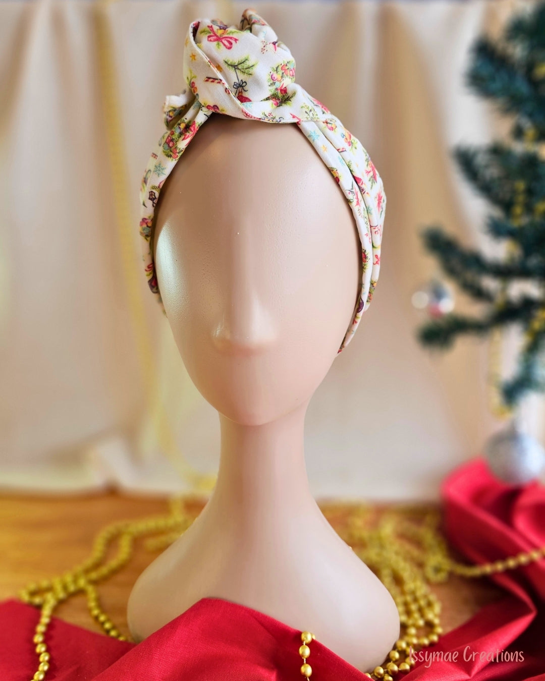 Vintage Greetings cream Christmas wire head wrap styled with a twisted top knot on a mannequin, front view.