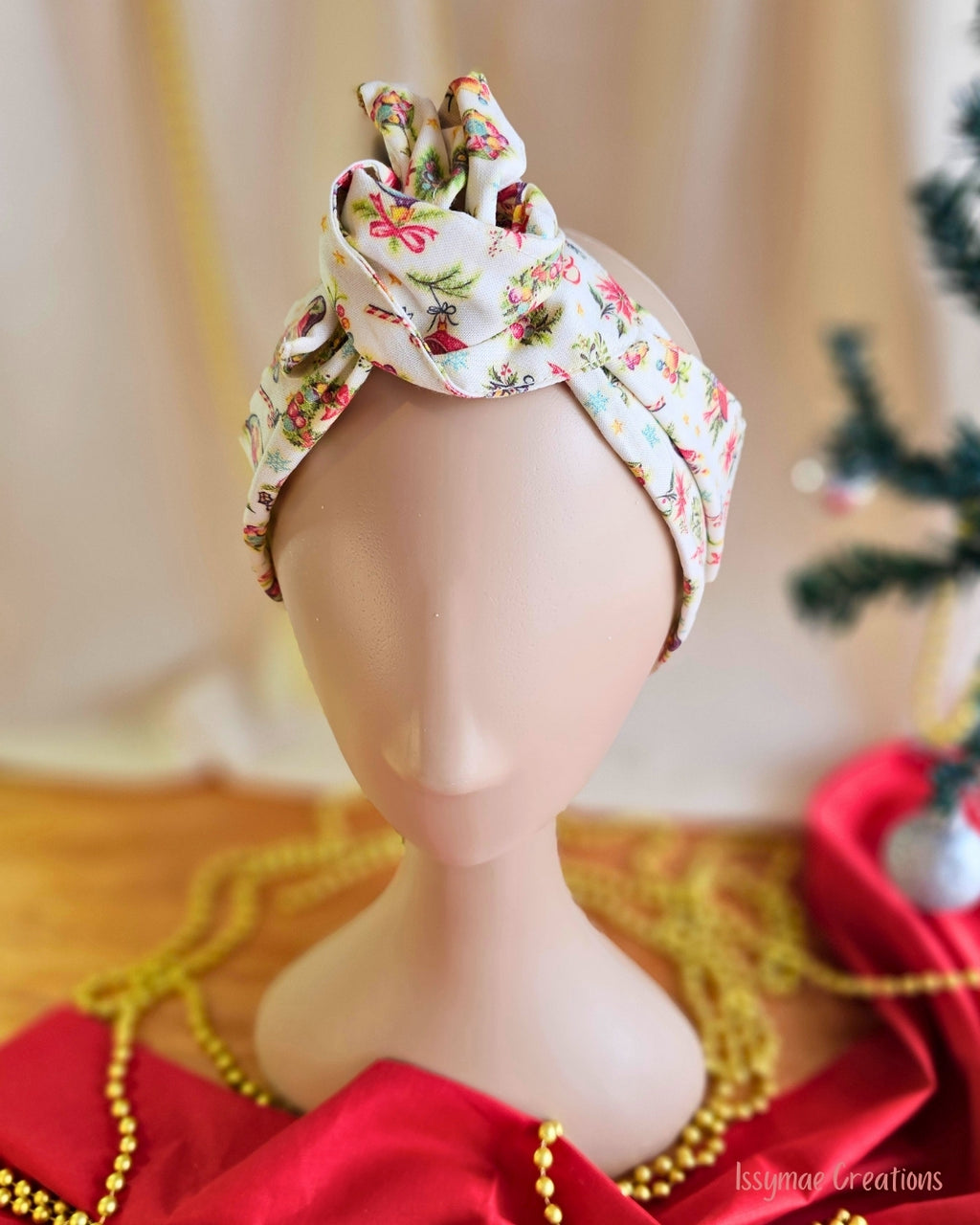  Close-up of the Vintage Greetings wire head wrap’s sculpted top knot and vintage Christmas print on cream fabric.