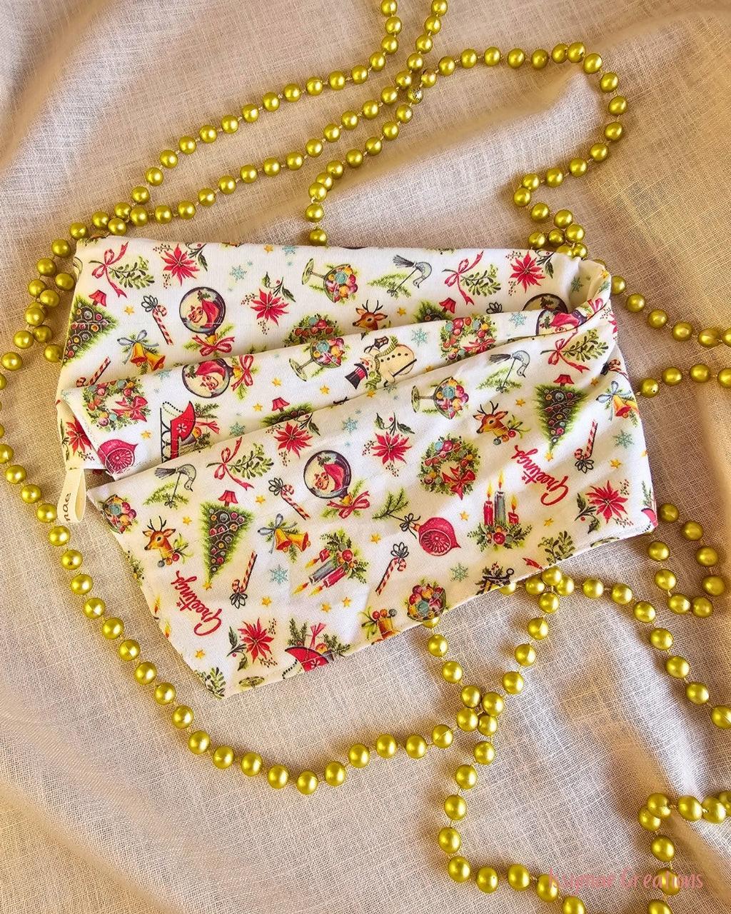 Vintage Greetings wire head wrap laid flat, showing poinsettias, baubles and Christmas illustrations on cream fabric.