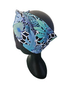 Blue and green patterned headband on a black mannequin head against a white background