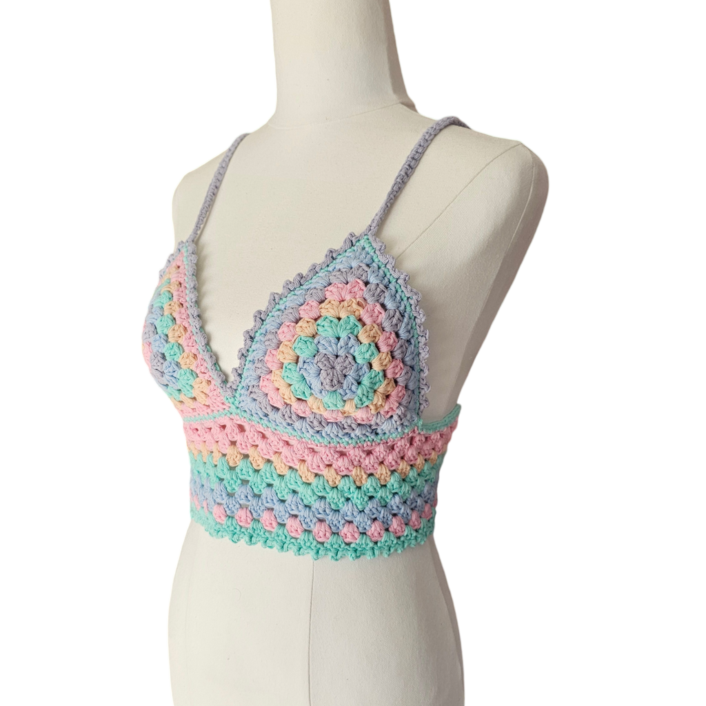 A multicolored crochet top displayed on a mannequin, featuring a geometric pattern with rainbow colors.