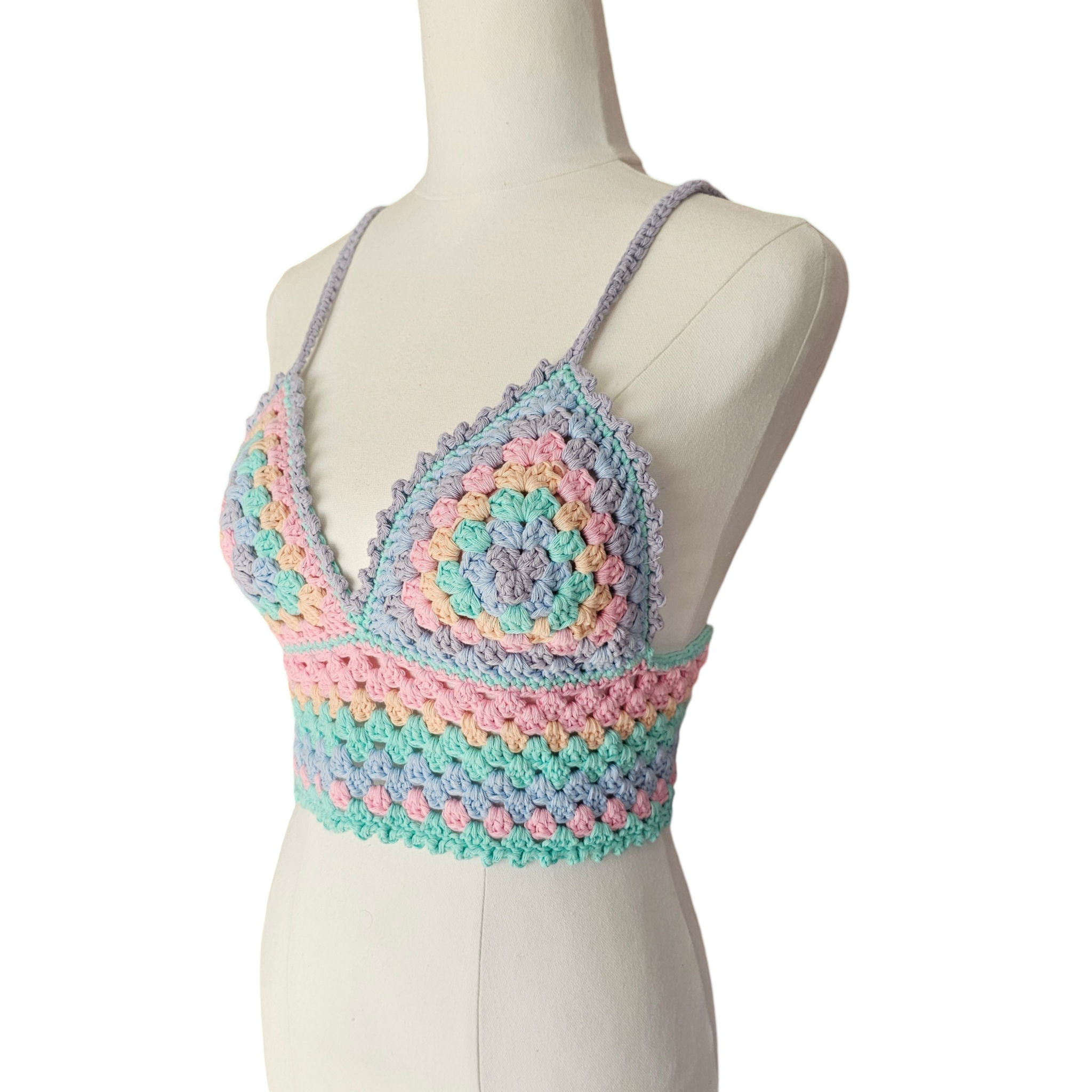 A multicolored crochet top displayed on a mannequin, featuring a geometric pattern with rainbow colors.