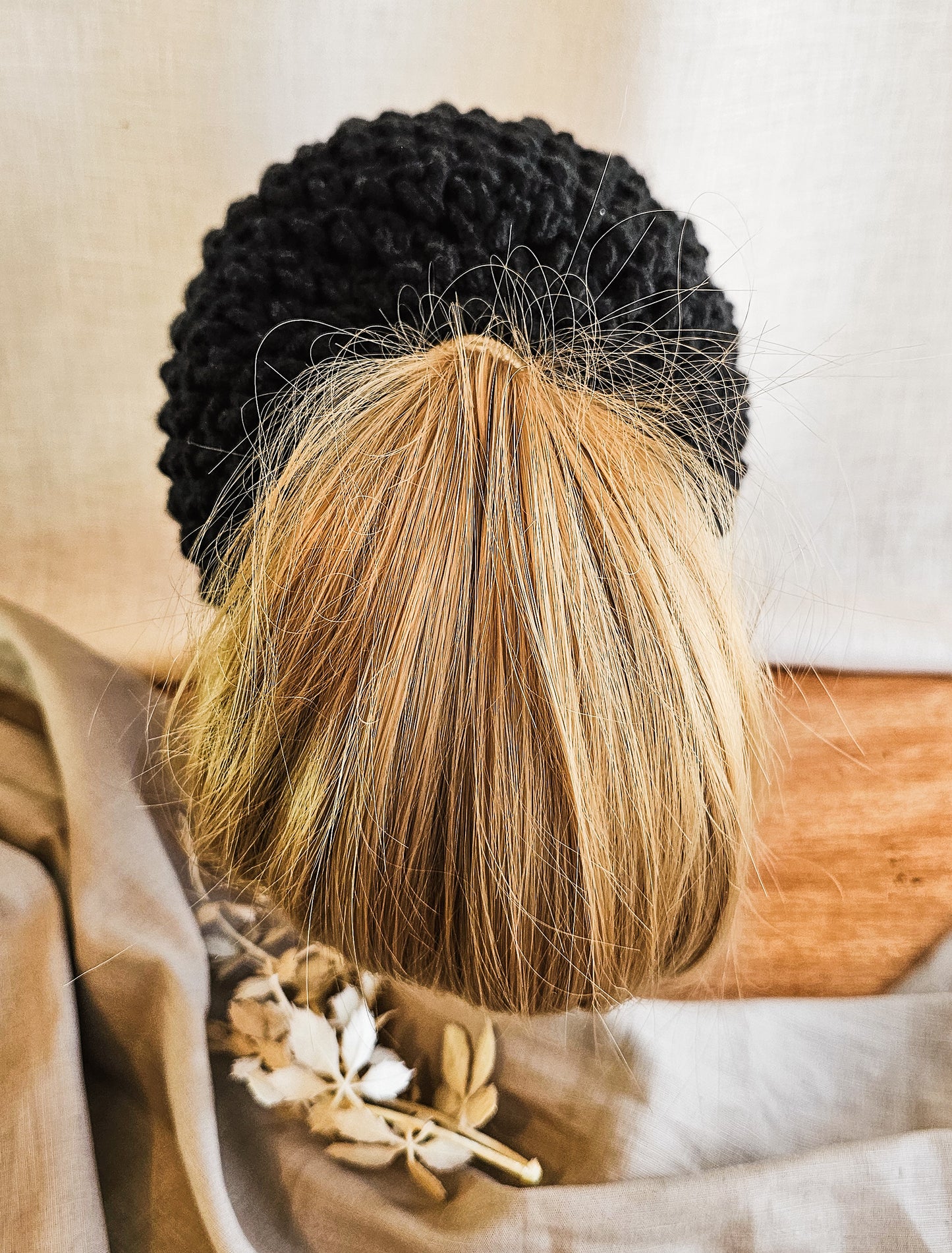 Person with black and blonde braided hair wearing a patterned garment.