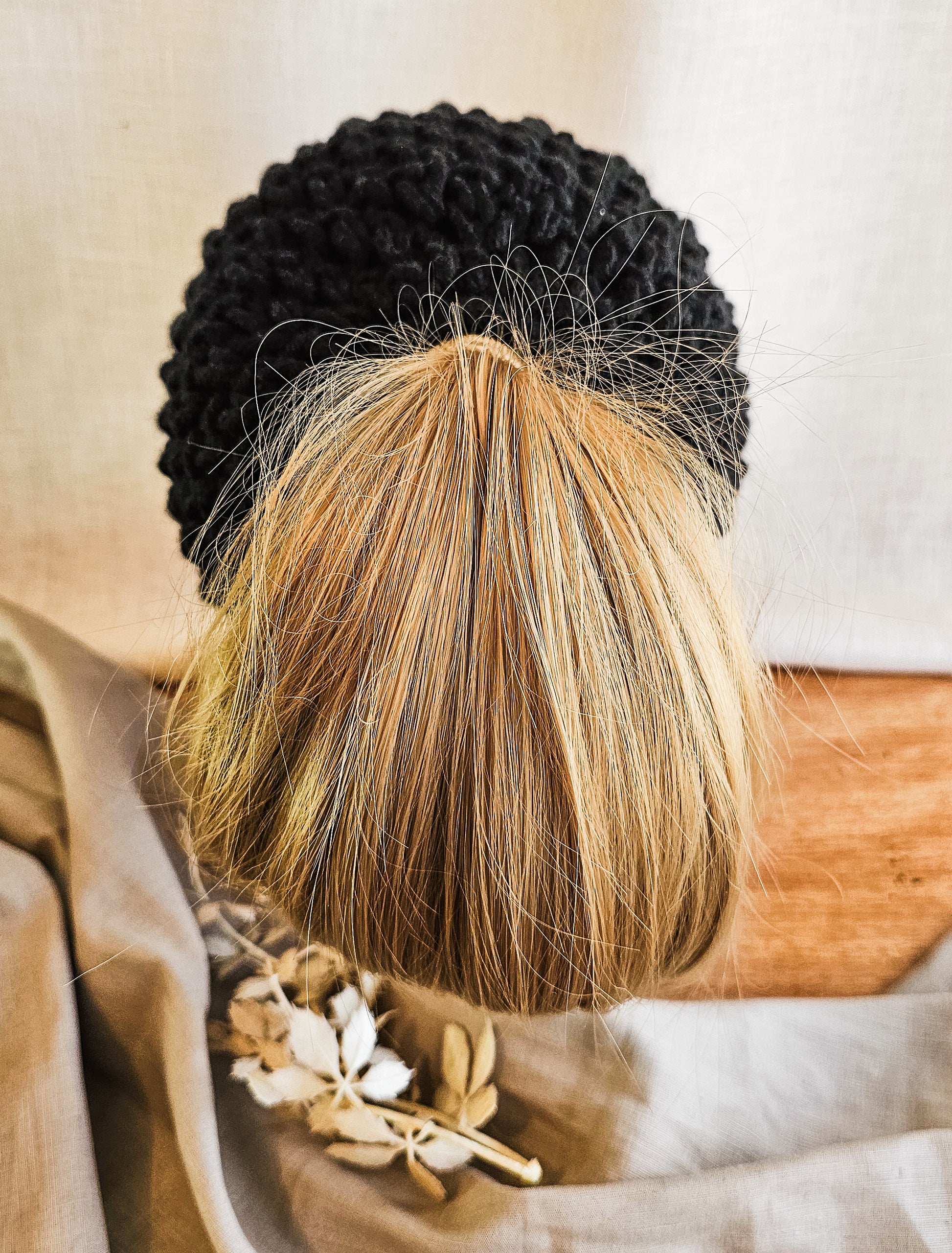Person with black and blonde braided hair wearing a patterned garment.
