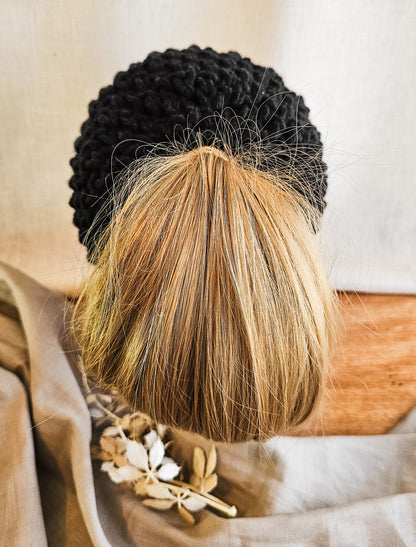 Person with black and blonde braided hair wearing a patterned garment.