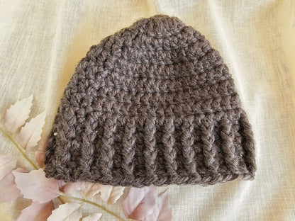 Brown knitted beanie on a light fabric background with floral elements