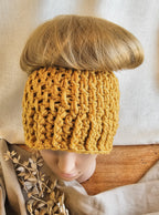 Person wearing a mustard yellow knitted headband with a neutral background