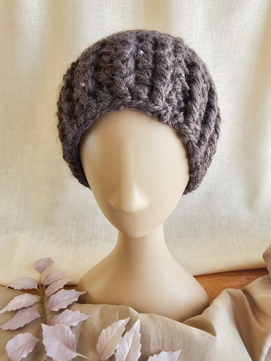 Knitted brown hat on a mannequin head against a neutral background