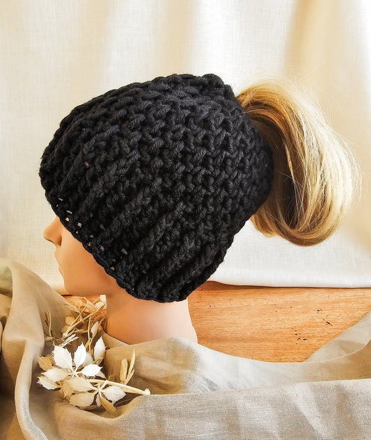Black knitted beanie worn by a mannequin head with a blurred background