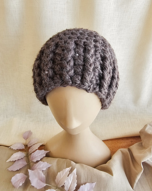 Knitted gray beanie on a mannequin head with a soft beige background