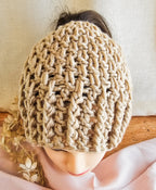 Beige knitted hat on a mannequin head with a neutral background