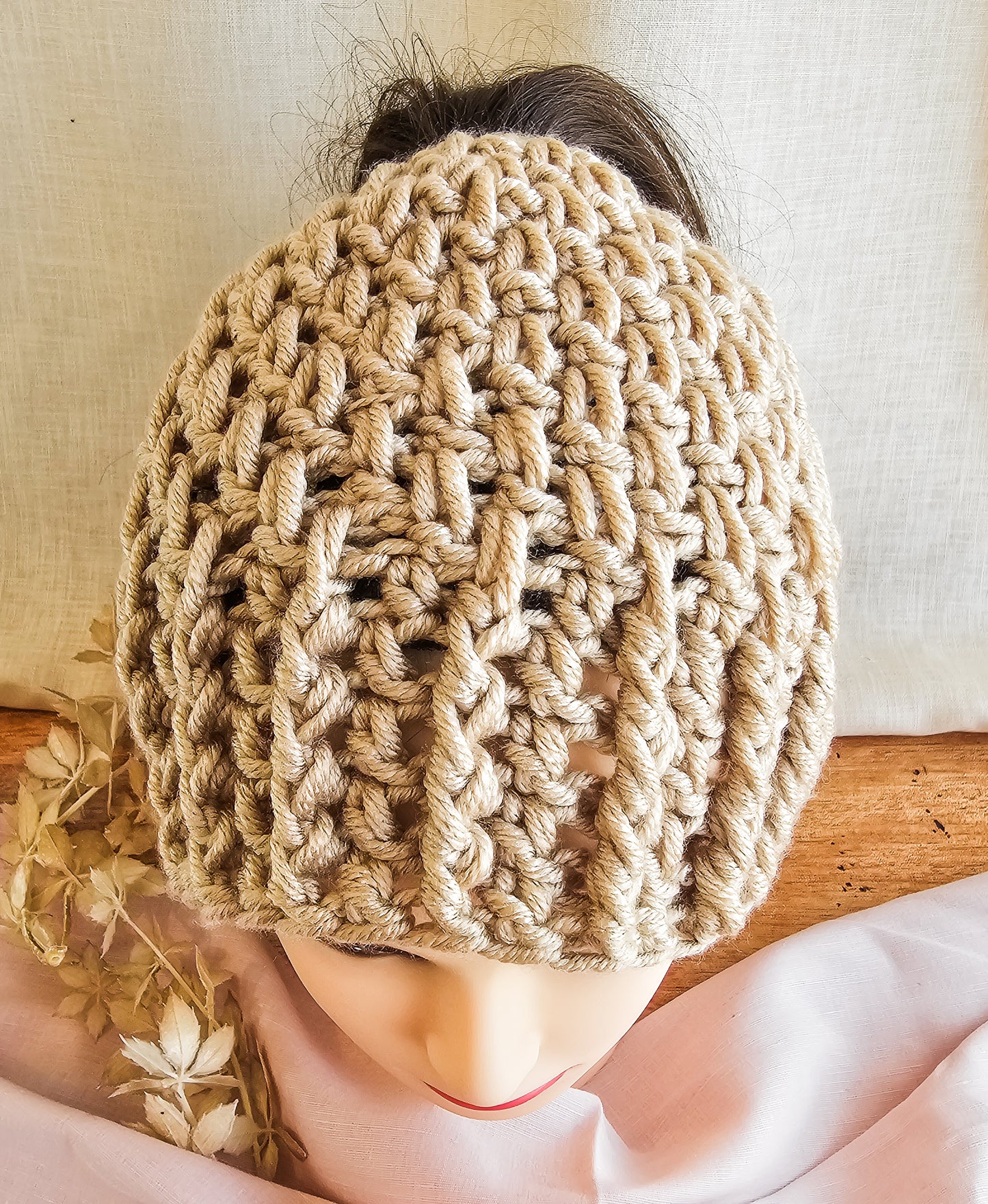 Beige knitted hat on a mannequin head with a neutral background