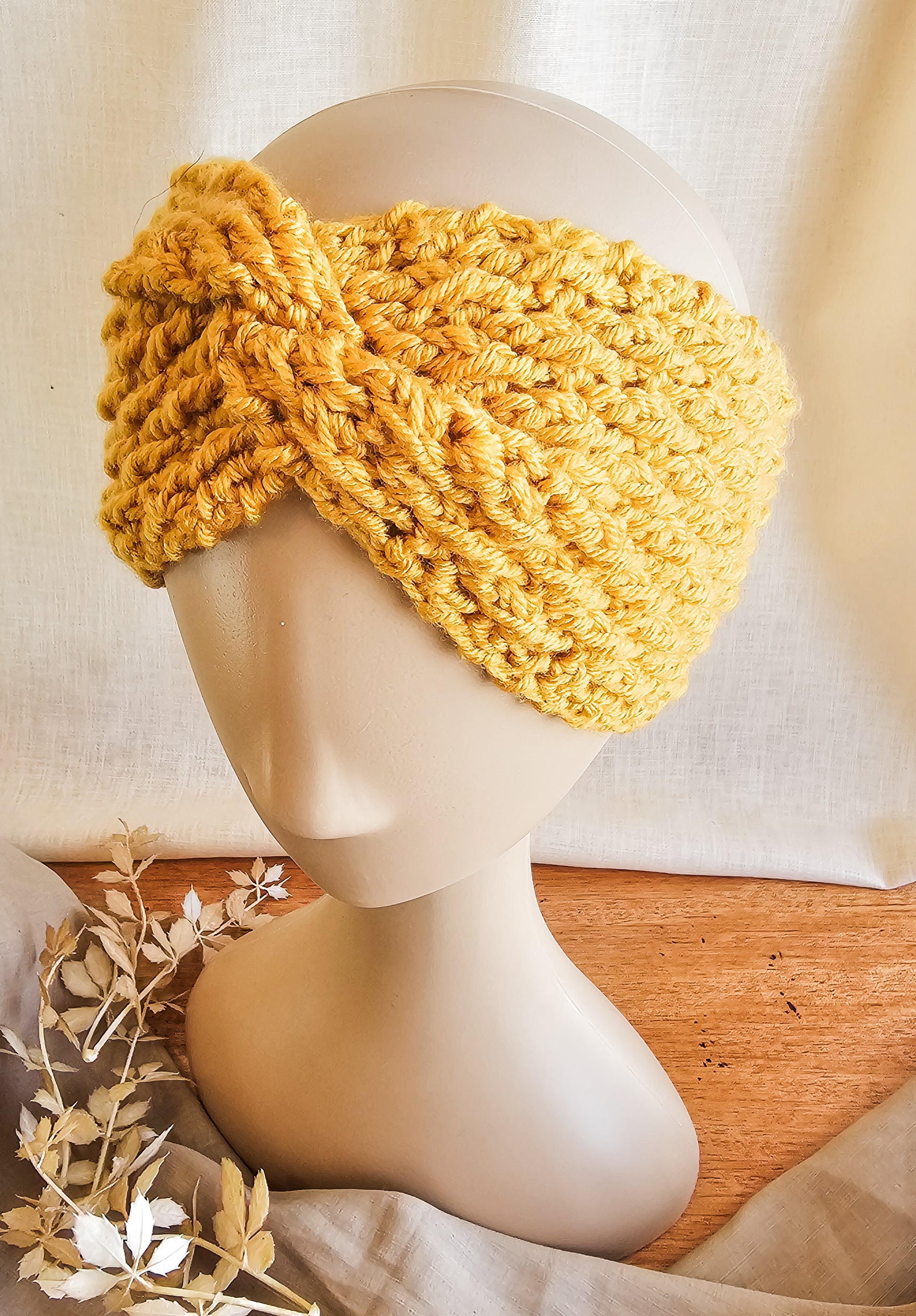 Yellow knitted headband on a mannequin head with a neutral background