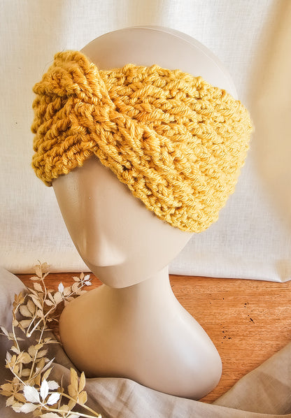 Yellow knitted headband on a mannequin head with a neutral background