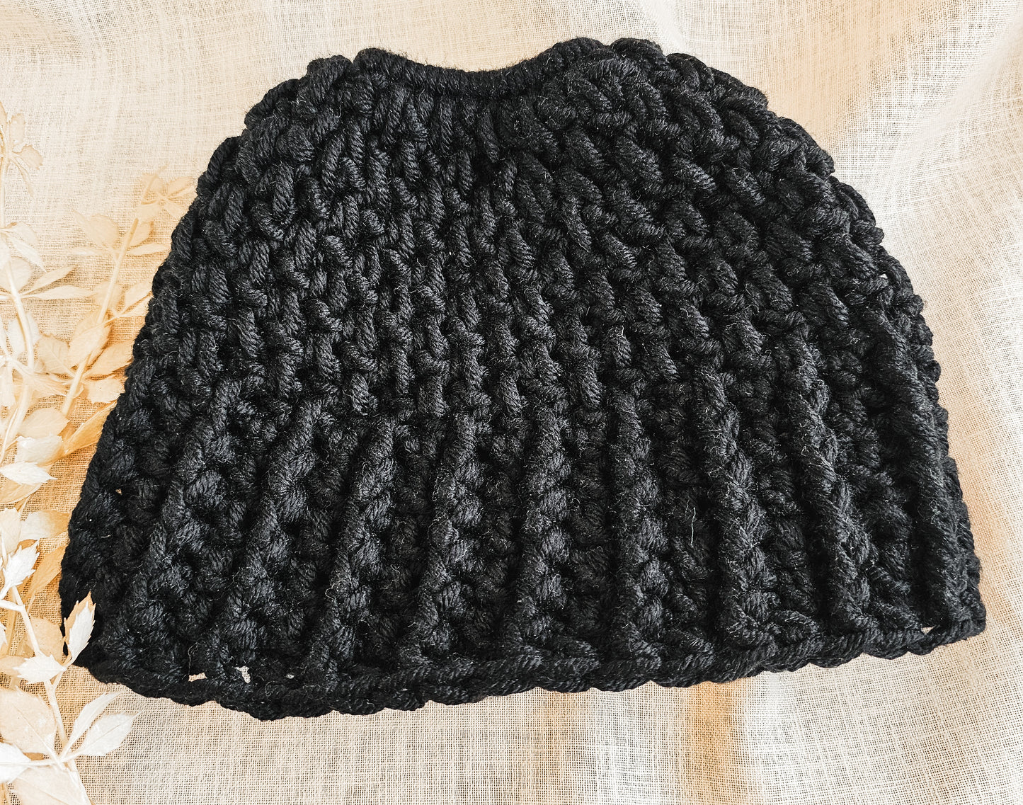 Black knitted beanie on a textured beige surface