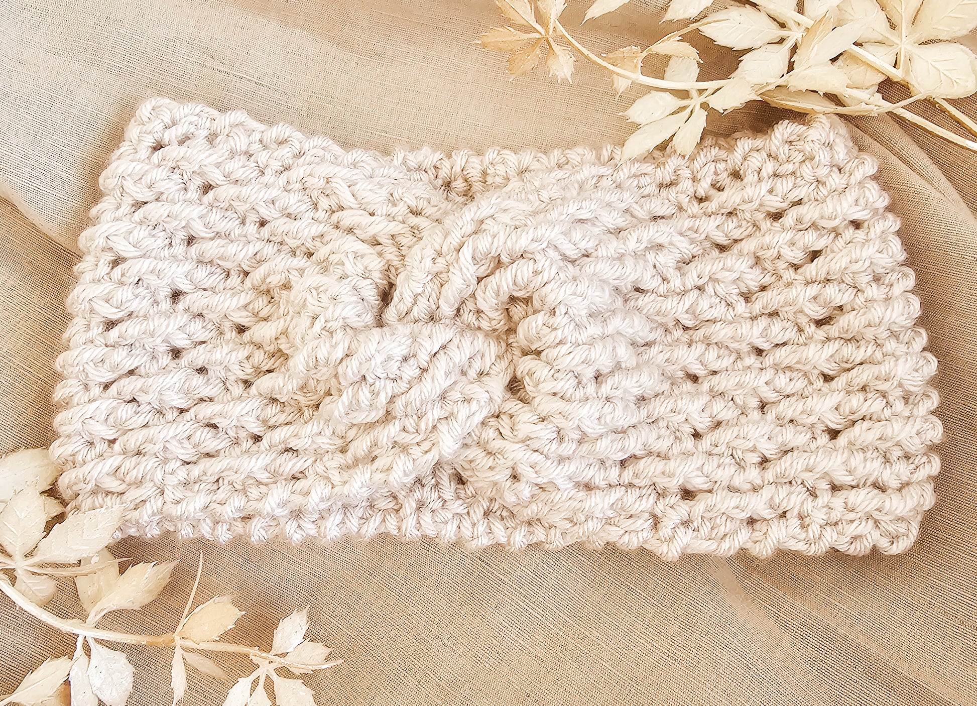 Beige knitted headband on a beige fabric background with floral elements