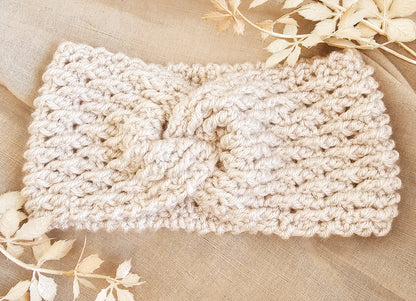 Beige knitted headband on a beige fabric background with floral elements