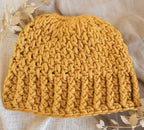 Yellow knitted beanie on a light fabric background