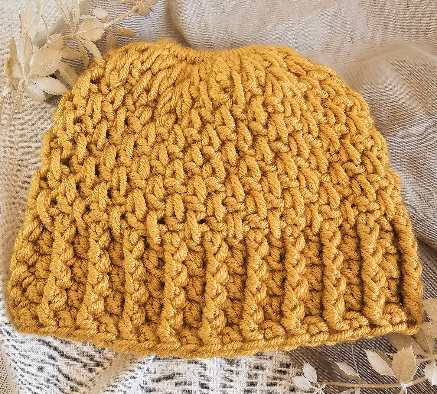 Yellow knitted beanie on a light fabric background