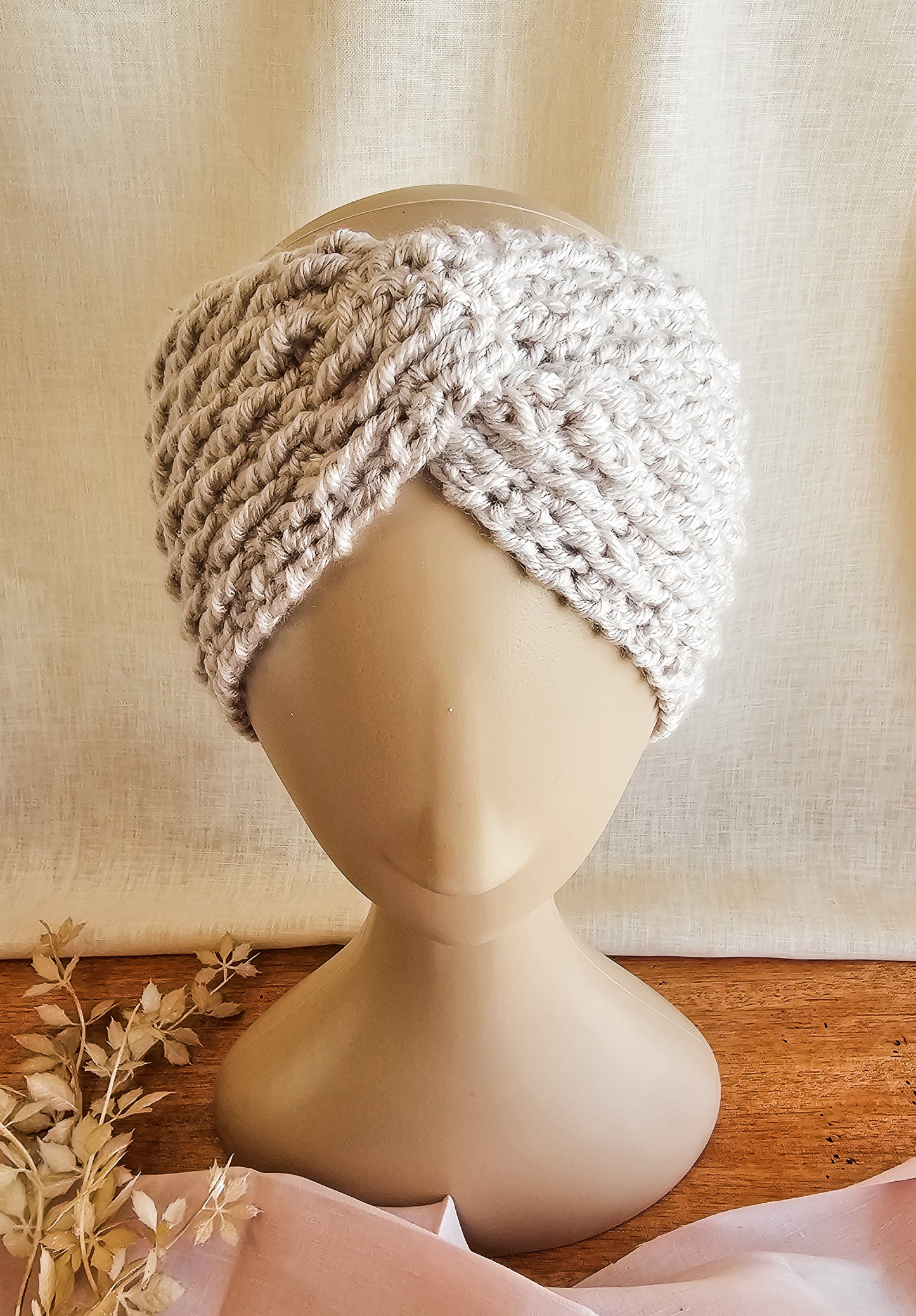 Knitted turban on a mannequin head against a beige background